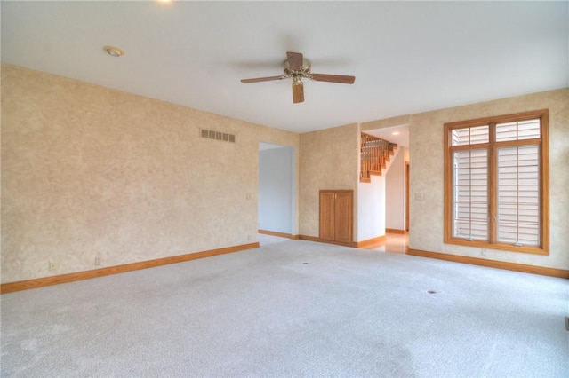 unfurnished room with carpet flooring, a ceiling fan, visible vents, stairs, and baseboards