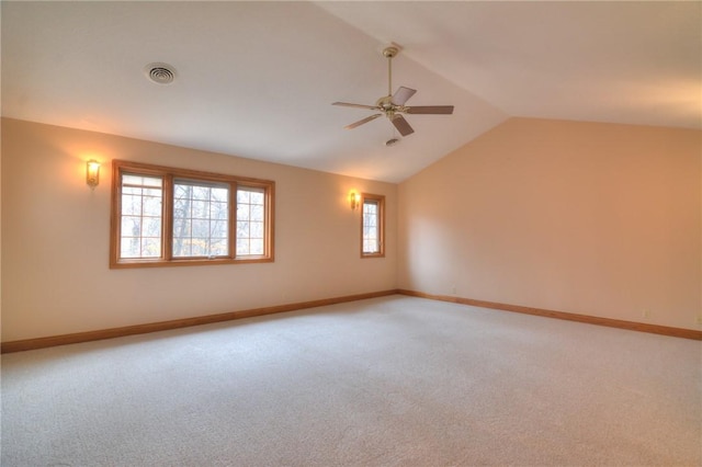 spare room featuring vaulted ceiling, baseboards, visible vents, and light colored carpet