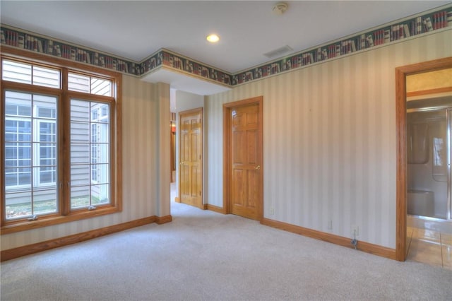 carpeted spare room featuring wallpapered walls, visible vents, and baseboards