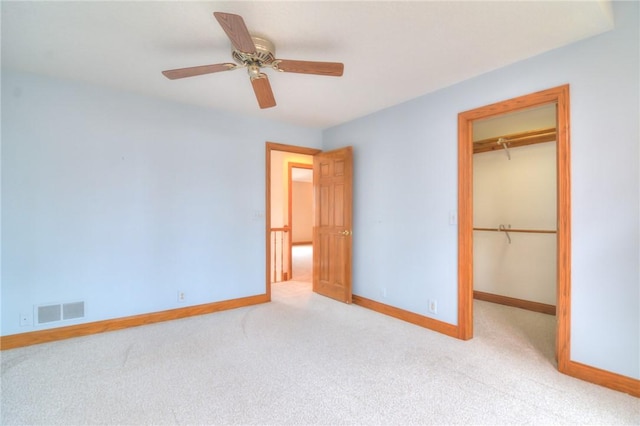 unfurnished bedroom with carpet floors, visible vents, baseboards, a closet, and a walk in closet