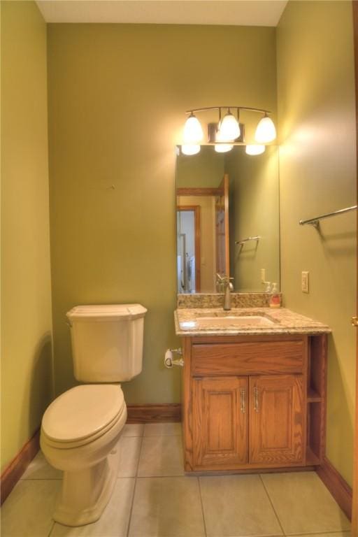 half bathroom featuring tile patterned flooring, baseboards, vanity, and toilet