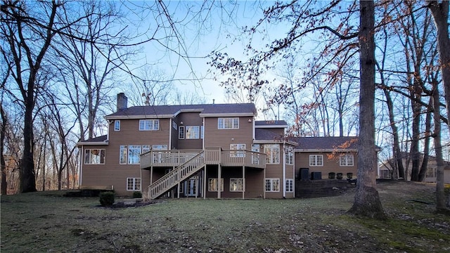 back of property featuring a chimney, stairway, a deck, and a lawn