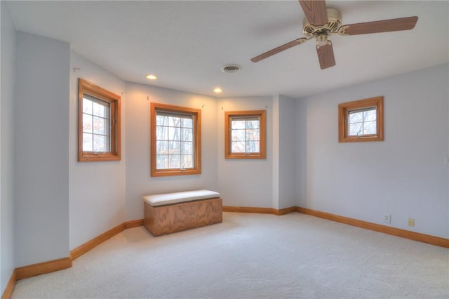 unfurnished room with baseboards, visible vents, a wealth of natural light, and light colored carpet