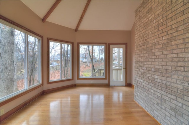 unfurnished sunroom featuring lofted ceiling with beams