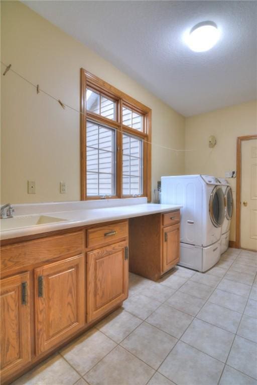 laundry room with a sink, light tile patterned floors, washing machine and clothes dryer, and cabinet space