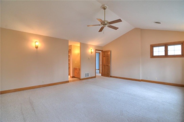 empty room with lofted ceiling, light carpet, visible vents, and baseboards