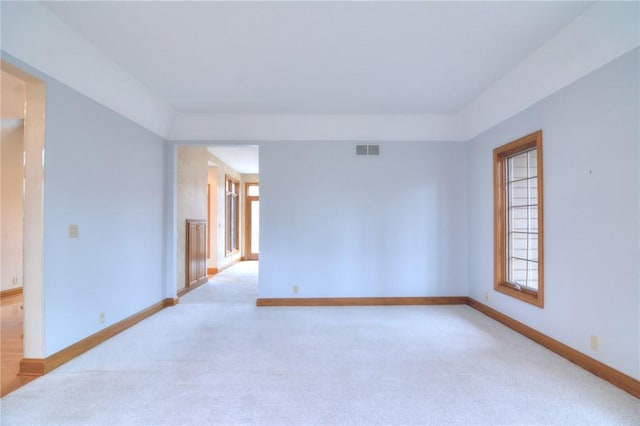 unfurnished room with visible vents, light carpet, and baseboards