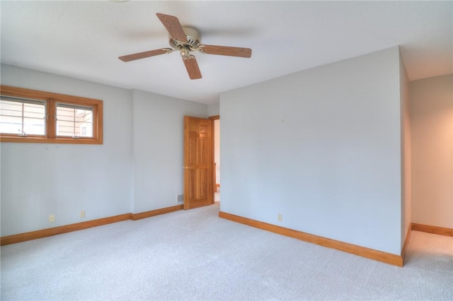 unfurnished room with ceiling fan, light colored carpet, and baseboards