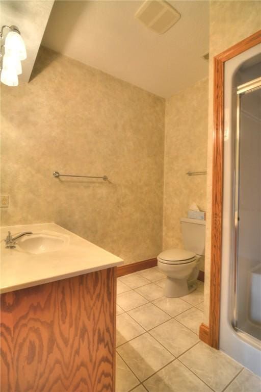 bathroom with a shower with door, vanity, toilet, and tile patterned floors