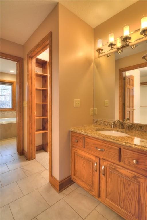 bathroom featuring a bath, tile patterned flooring, vanity, and baseboards