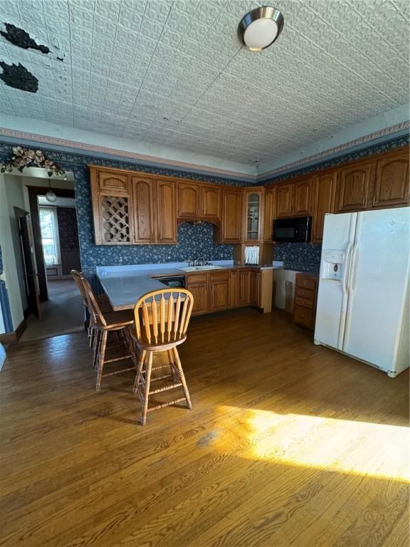 kitchen with backsplash, sink, wood-type flooring, and white fridge with ice dispenser