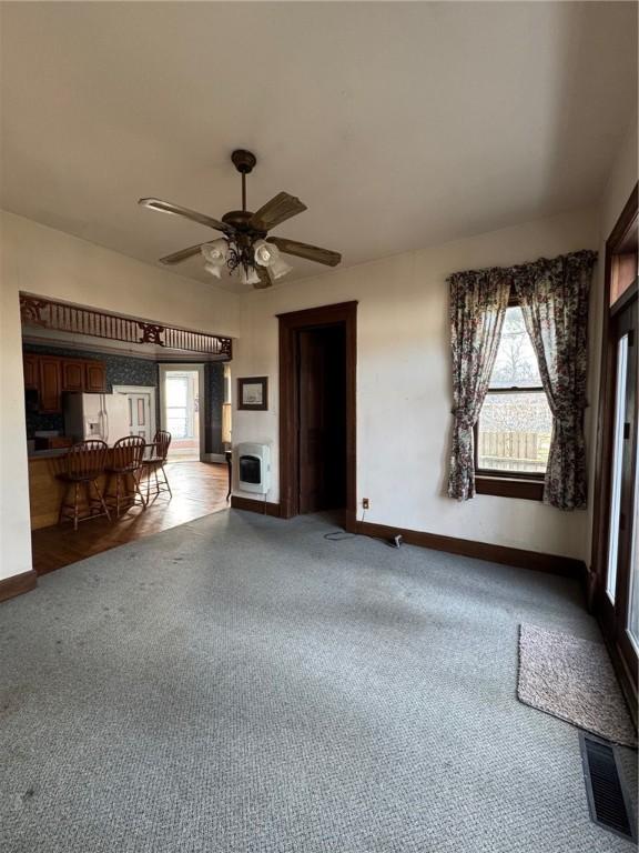 unfurnished living room featuring ceiling fan, carpet flooring, and heating unit