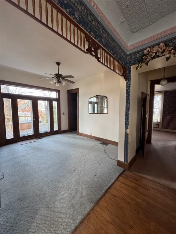 unfurnished living room with ceiling fan, carpet flooring, and a high ceiling