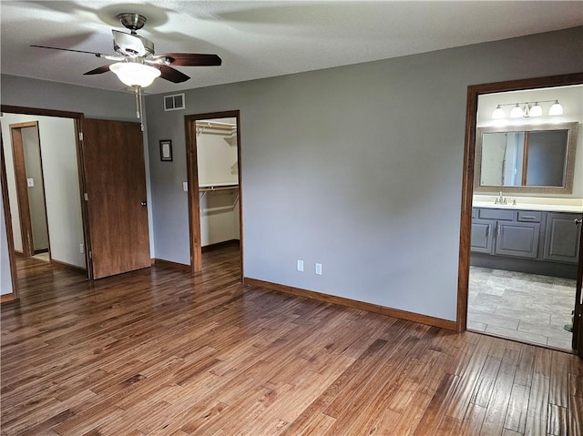 504 W Walnut St, Teutopolis, IL 62467 - unfurnished bedroom with light wood finished floors, a spacious closet, ensuite bath, and ceiling fan