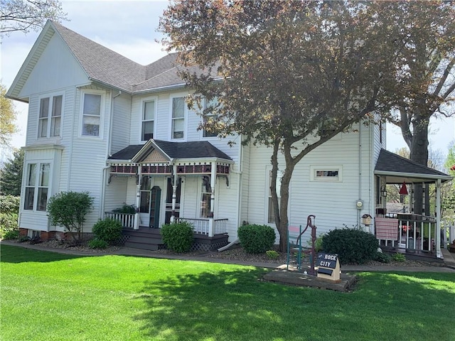 view of front of house with a porch, roof with shingles, and a front lawn