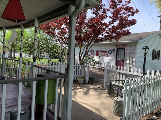 view of patio featuring fence and a porch