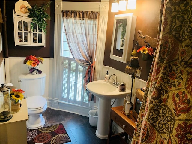 bathroom with tile patterned flooring, wainscoting, and toilet