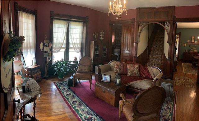 living room featuring an inviting chandelier, wood finished floors, and stairway