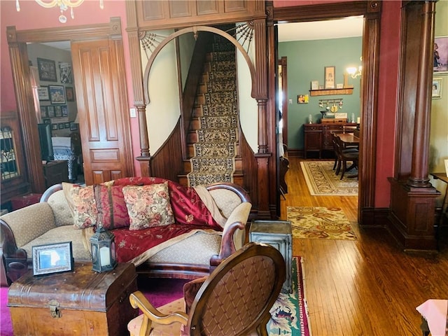 living room featuring decorative columns, hardwood / wood-style flooring, and stairway