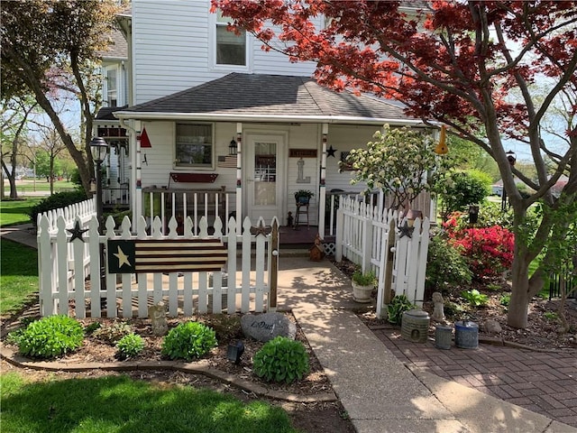 view of front of house featuring covered porch, fence, and a shingled roof