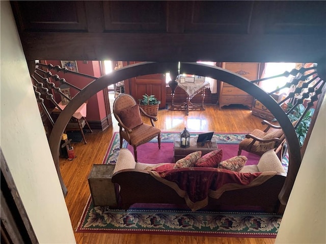 living area with arched walkways and wood finished floors