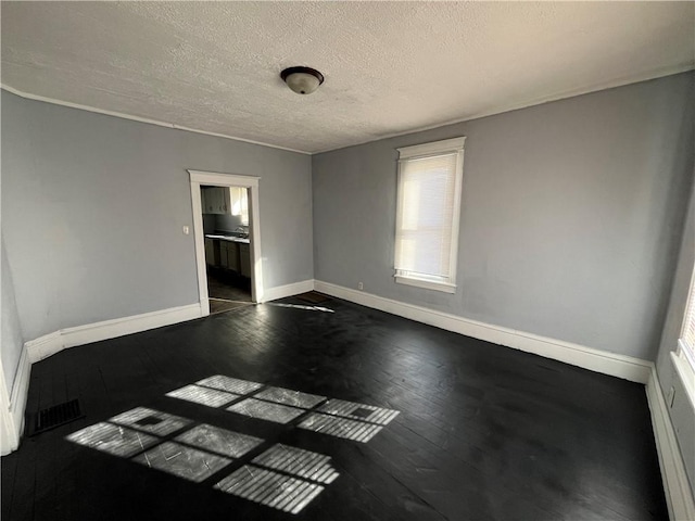 unfurnished room featuring dark wood-type flooring and a textured ceiling