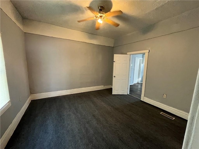 spare room with dark carpet, a textured ceiling, and ceiling fan