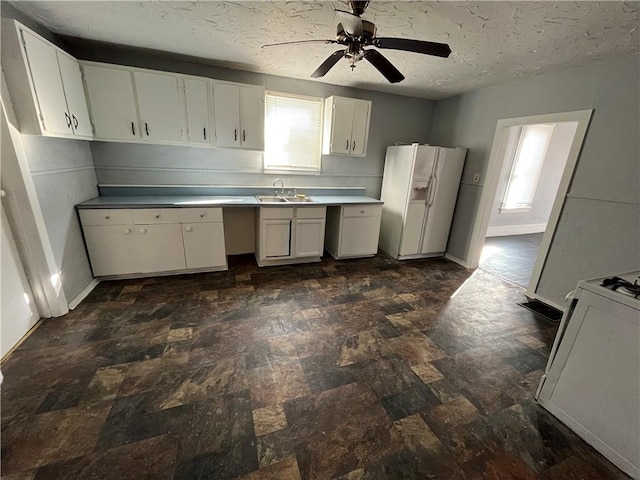 kitchen with white cabinetry, sink, white refrigerator with ice dispenser, stove, and a textured ceiling