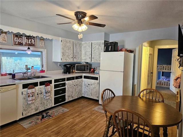 kitchen with white appliances, ceiling fan, dark wood-type flooring, sink, and white cabinets