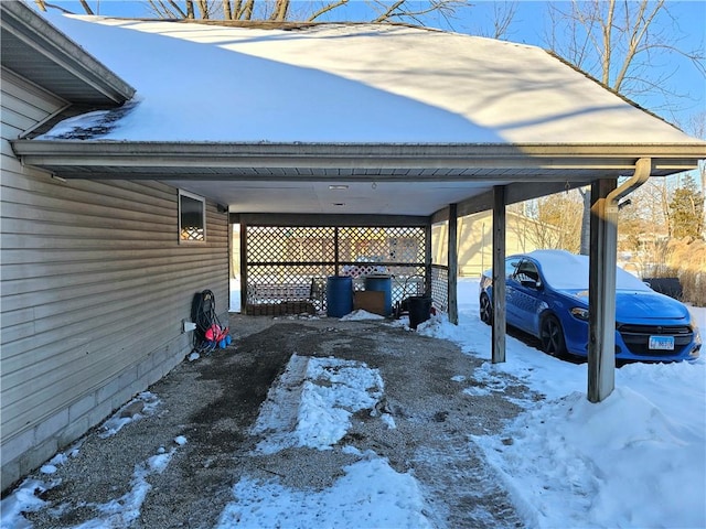 snow covered parking area featuring a carport