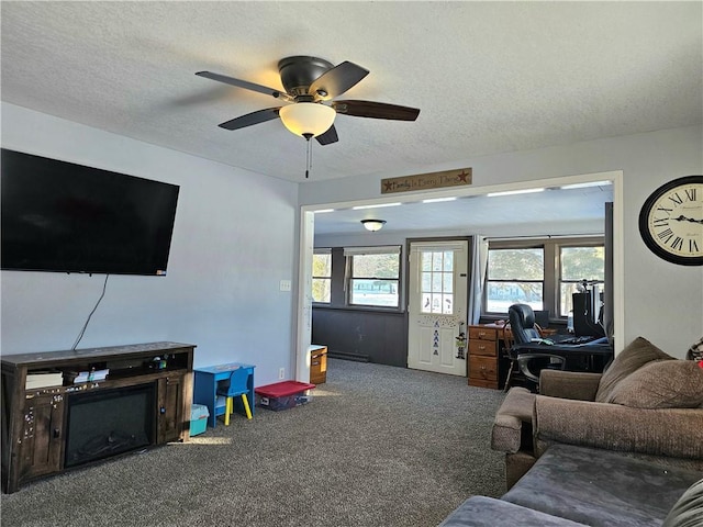 carpeted living room with ceiling fan and a textured ceiling