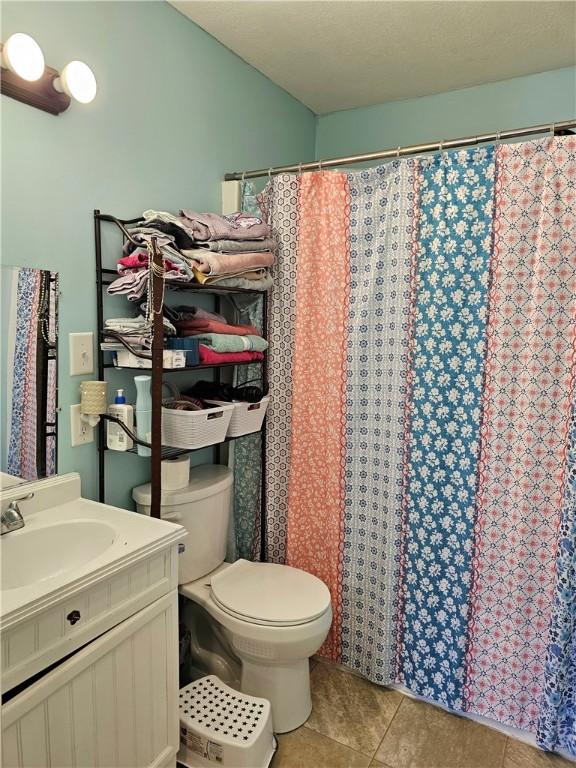 bathroom featuring a shower with curtain, vanity, toilet, and tile patterned floors