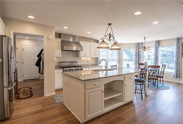 1117 Wedgewood Ct, Decatur, IL 62526 - kitchen with wall chimney range hood, freestanding refrigerator, wood finished floors, white cabinets, and recessed lighting