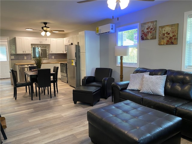 living room featuring a wall unit AC, ceiling fan, and light wood-type flooring