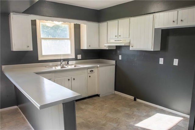 kitchen with white cabinets, kitchen peninsula, and sink