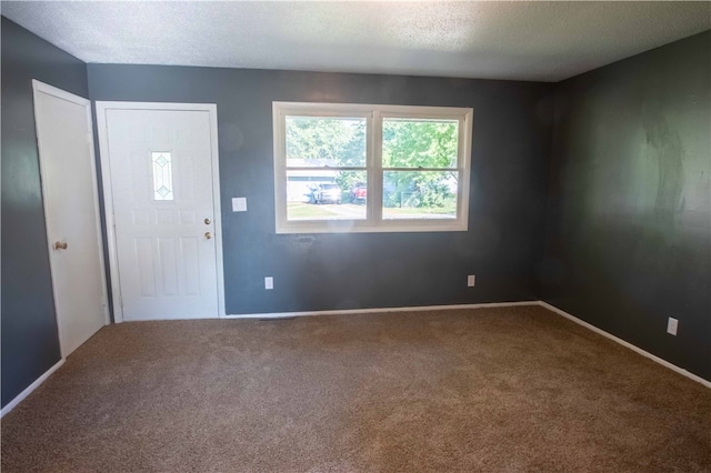 carpeted foyer entrance with a textured ceiling