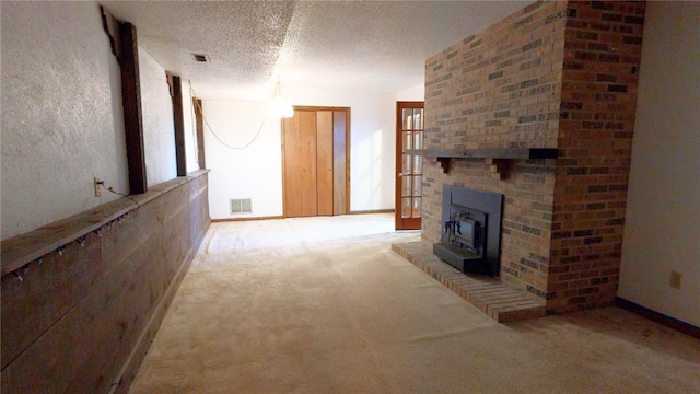 unfurnished living room with light colored carpet, a wood stove, and a textured ceiling