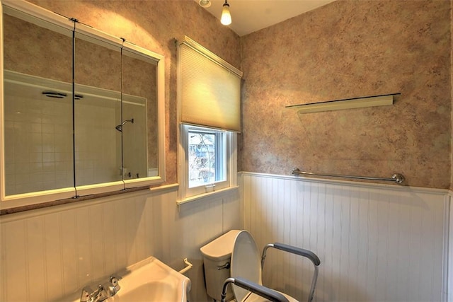 bathroom featuring tiled shower and toilet