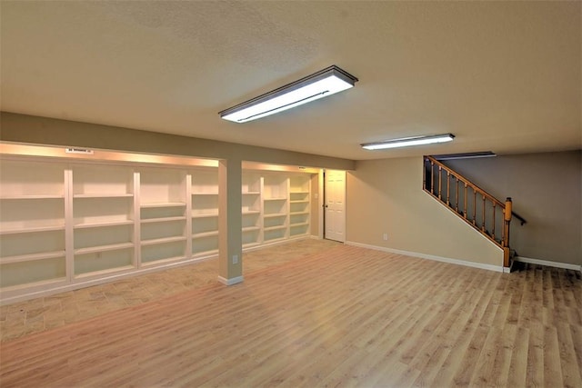 basement featuring wood-type flooring and a textured ceiling