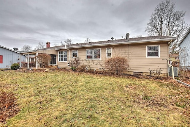 rear view of house featuring central AC unit and a yard