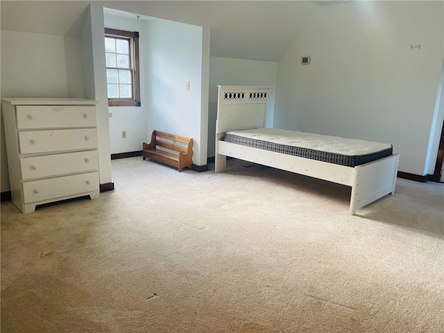 unfurnished bedroom featuring light carpet and lofted ceiling