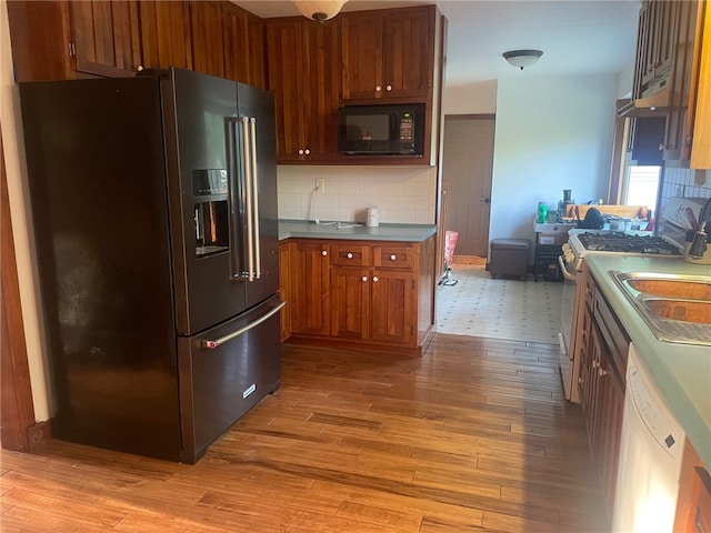 kitchen featuring light wood-type flooring, decorative backsplash, white appliances, and sink