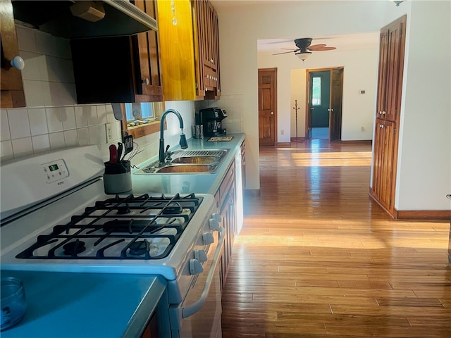 kitchen featuring sink, light hardwood / wood-style flooring, extractor fan, and white gas range oven