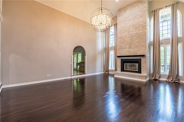 1250 W Hickory Point Rd, Decatur, IL 62526 - unfurnished living room with arched walkways, a chandelier, a high ceiling, plenty of natural light, and wood finished floors