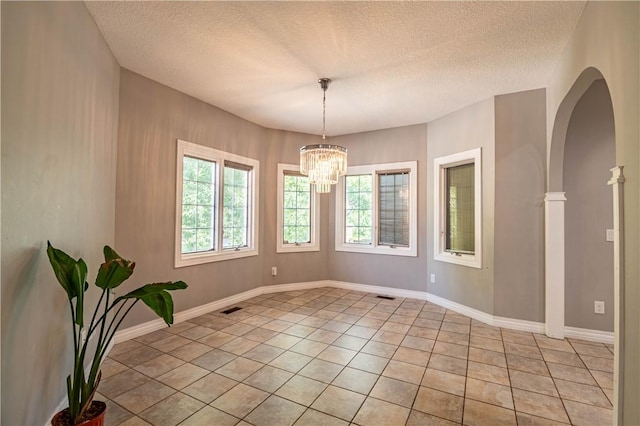 1250 W Hickory Point Rd, Decatur, IL 62526 - spare room featuring a textured ceiling, a chandelier, arched walkways, and light tile patterned floors