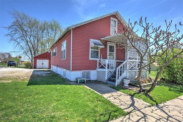 view of front facade with a front lawn, covered porch, an outbuilding, and a garage