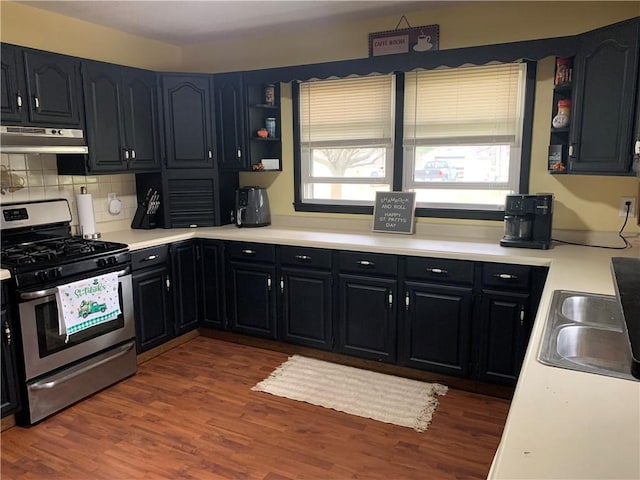 201 Franklin St, Pana, IL 62557 - kitchen with under cabinet range hood, stainless steel range with gas stovetop, a wealth of natural light, and dark wood-style floors