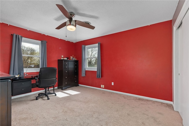 carpeted home office with ceiling fan, a healthy amount of sunlight, and a textured ceiling