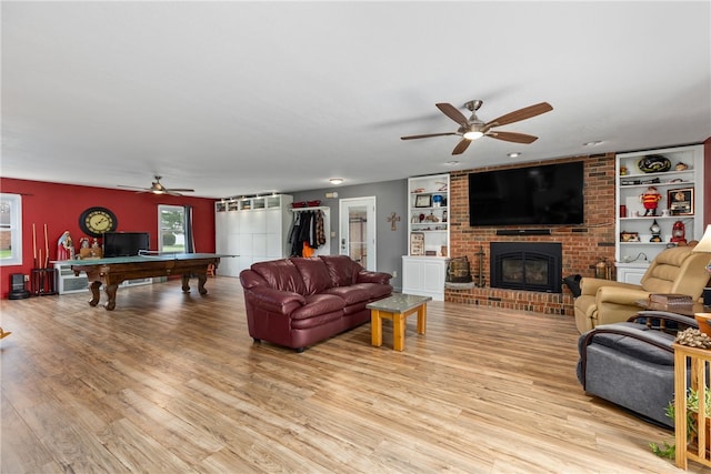 living room with ceiling fan, light hardwood / wood-style flooring, built in features, billiards, and a fireplace