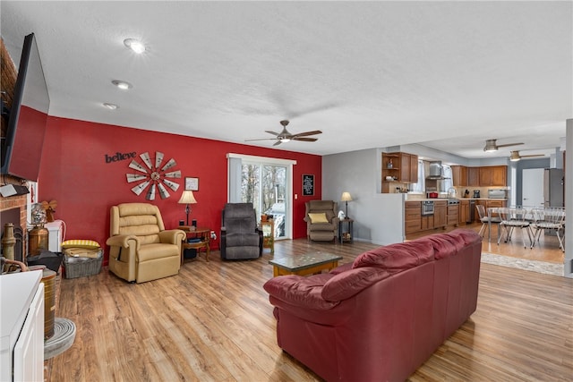 living room with ceiling fan, a textured ceiling, and light hardwood / wood-style flooring